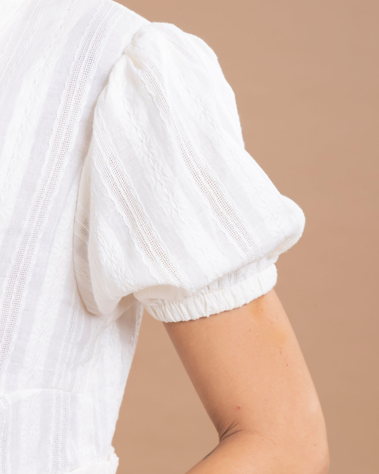 Blusa insignia de la marca, con mangas globo y bolero en la parte inferior que aportan volumen y movimiento. En el frente, cuenta con tiras para anudar en un moño, creando un detalle femenino y elegante.