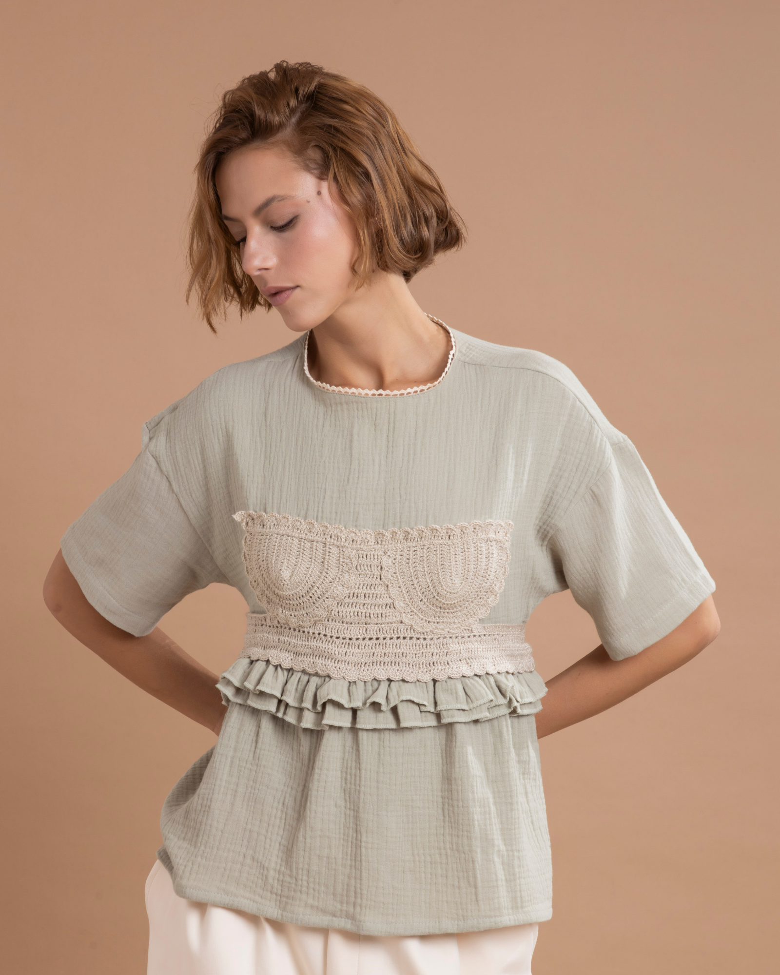 Camisa estilo t-shirt confeccionada en algodón, con un aplique en forma de top elaborado en técnica crochet, 100% tejido a mano. Presenta boleros decorativos a la altura de la cintura y tiras posteriores que salen desde los costados, permitiendo ajustarla y anudarla con un moño en la parte trasera.