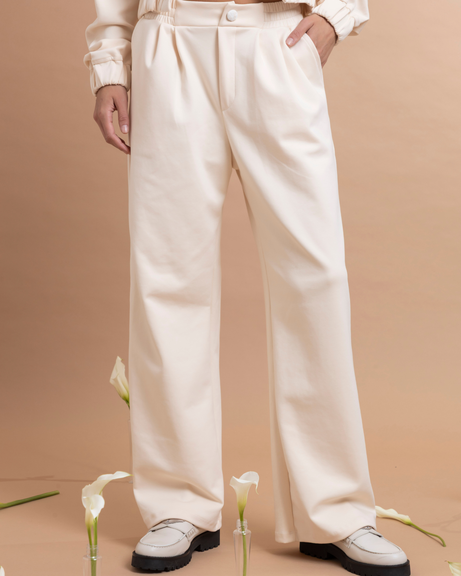 Pantalón con pinzas confeccionado en tela tipo sudadera, que combina comodidad y una apariencia elegante. Presenta bolsillos traseros elaborados en una tela con textura bordada y pretina con elástico para un mejor ajuste a la cintura.