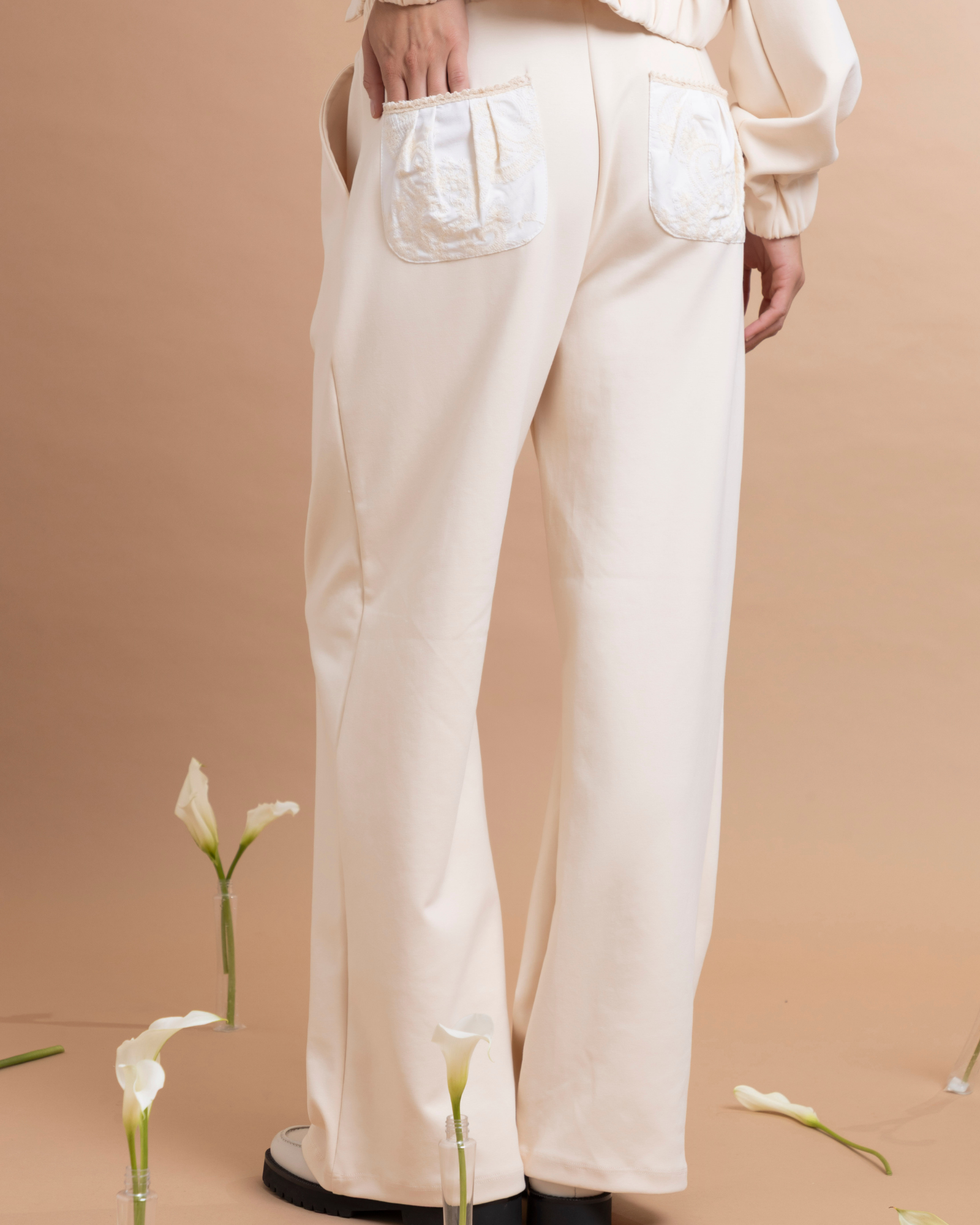 Pantalón con pinzas confeccionado en tela tipo sudadera, que combina comodidad y una apariencia elegante. Presenta bolsillos traseros elaborados en una tela con textura bordada y pretina con elástico para un mejor ajuste a la cintura.