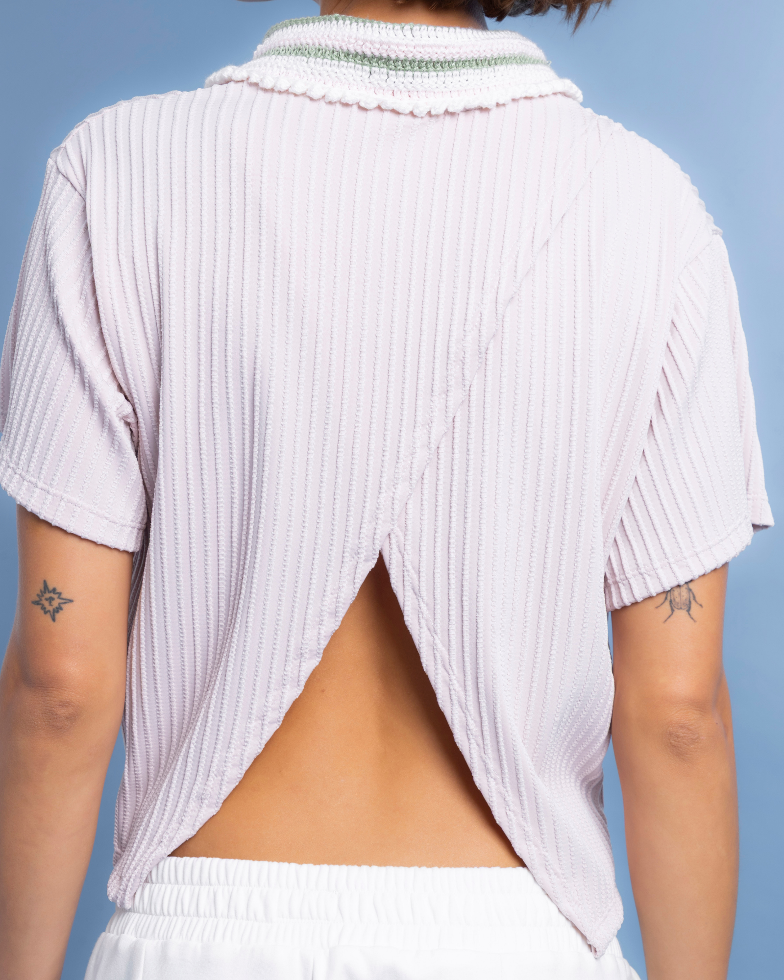 Camisa tipo polo confeccionada en lycra con textura, de horma oversized. Su cuello, tejido 100% a mano en crochet. Con abertura en la parte posterior de la prenda.&nbsp;