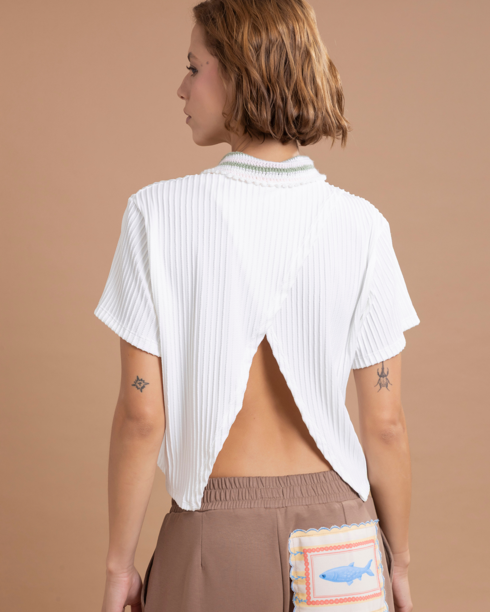 Camisa tipo polo confeccionada en lycra con textura, de horma oversized. Su cuello, tejido 100% a mano en crochet. Con abertura en la parte posterior de la prenda.