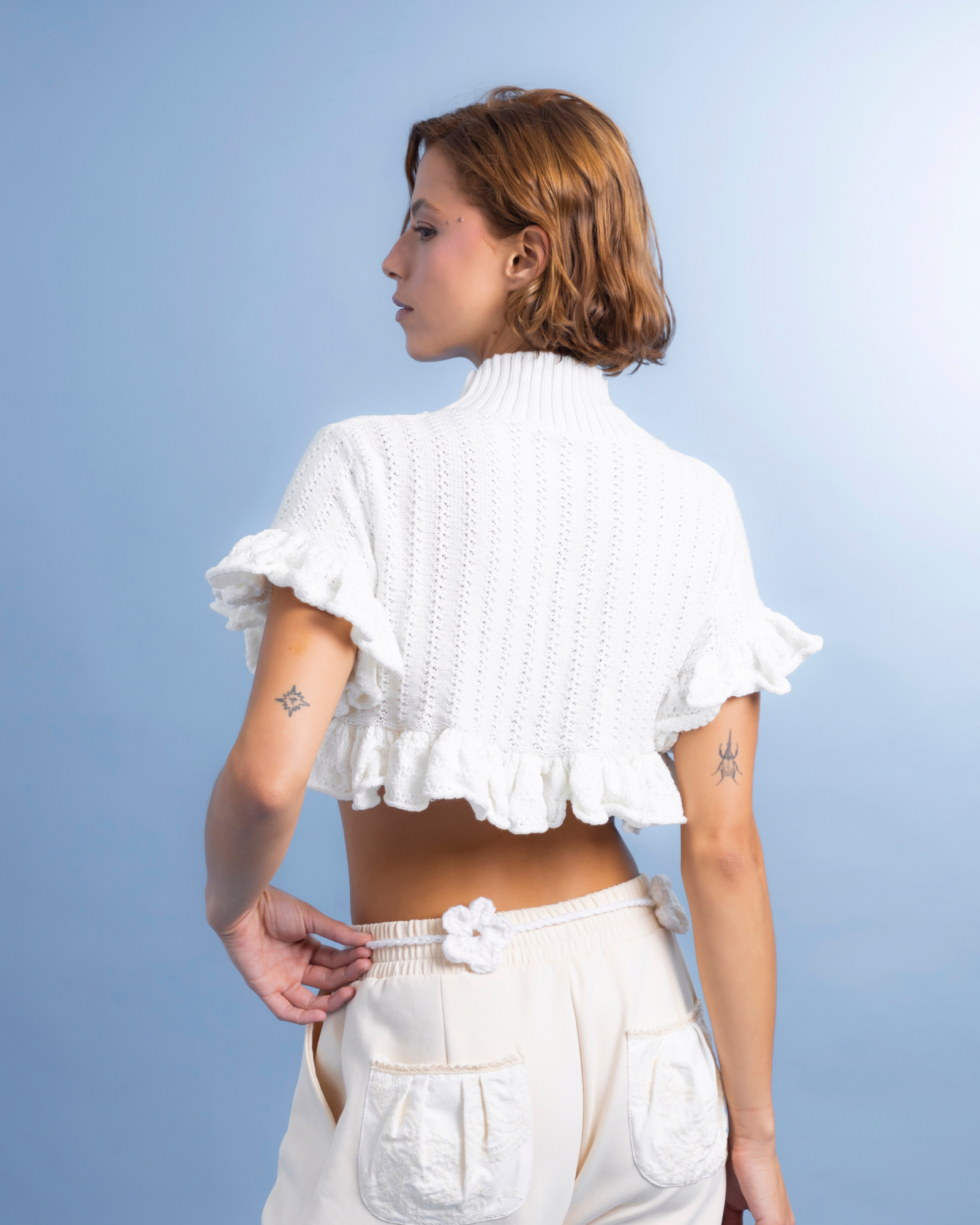 Prenda tejida en algodón, de cuello alto y corte corto, ideal para usar como crop top o como sobrepuesto. La parte inferior cuenta con boleros que aportan movimiento y un detalle femenino.